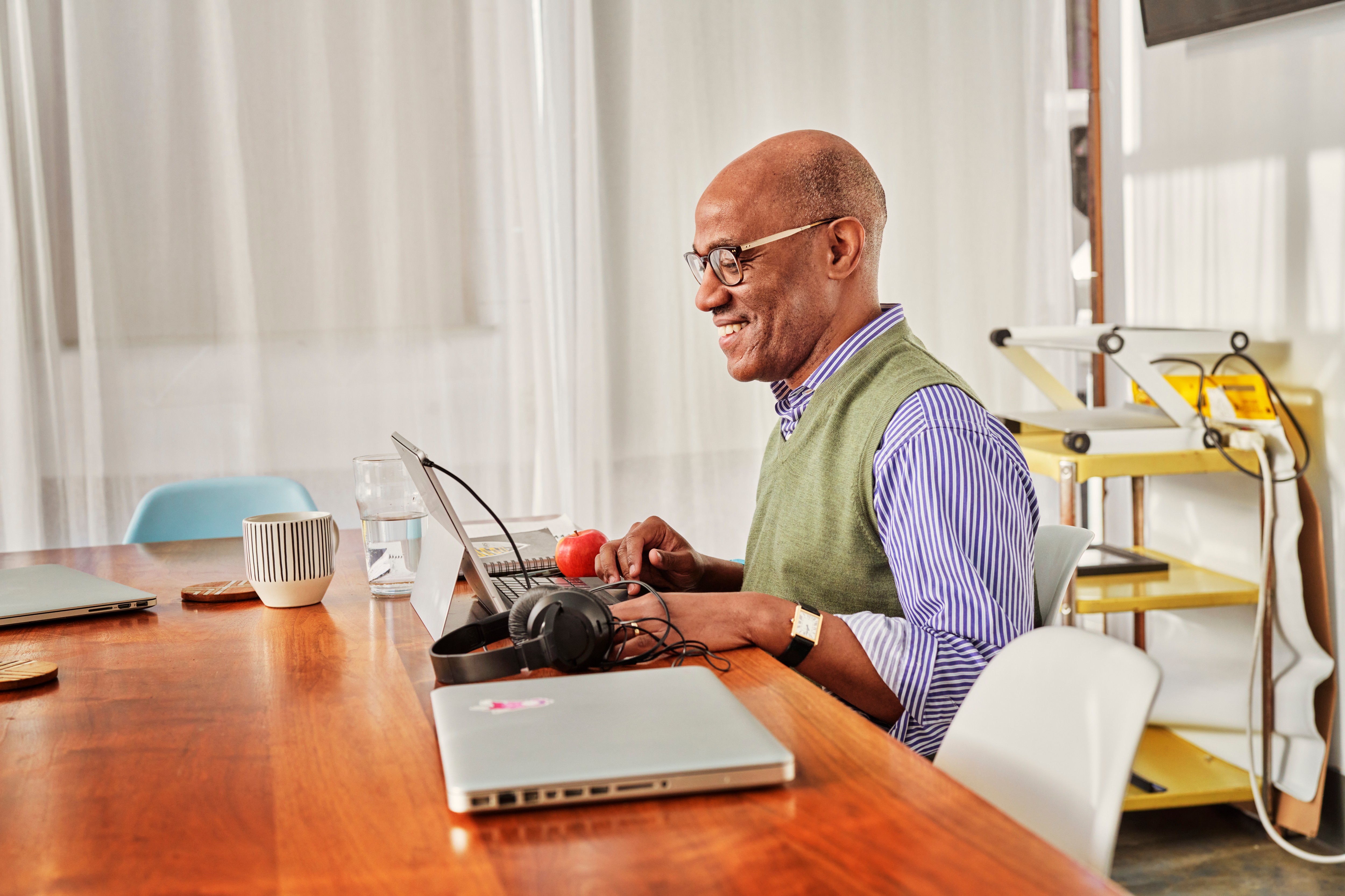 Image of a smiling man sitting in front of a laptop.