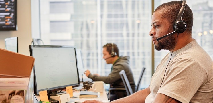 An image of a man wearing a headset working at an office.